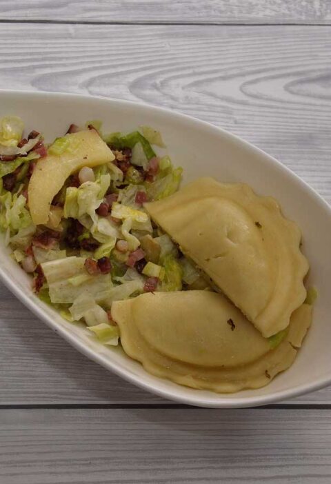 Appel spek salade met ravioli in een wit schaaltje.