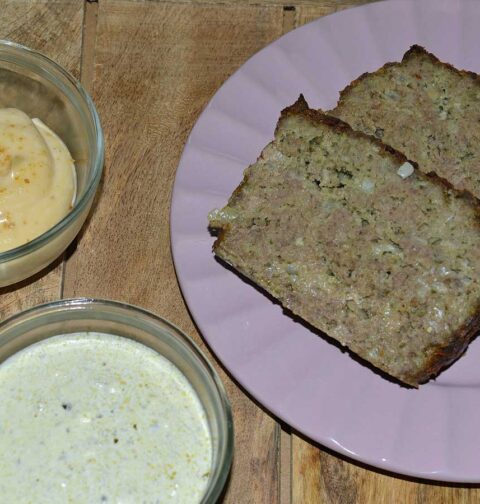 2 plakken gehaktbrood pesto met basilicumsaus op een paars bordje. met sauzen.