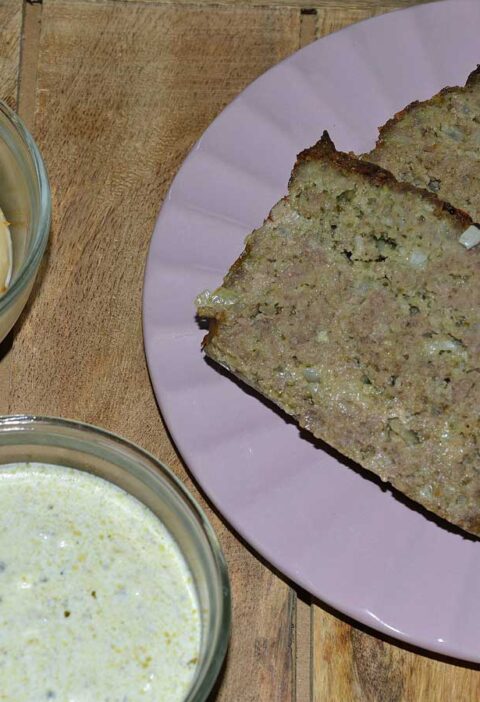2 plakken gehaktbrood pesto met basilicumsaus op een paars bordje. met sauzen.