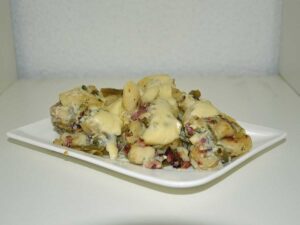 Gnocchi carbonara met bonen op een rechthoekig wit bordje.