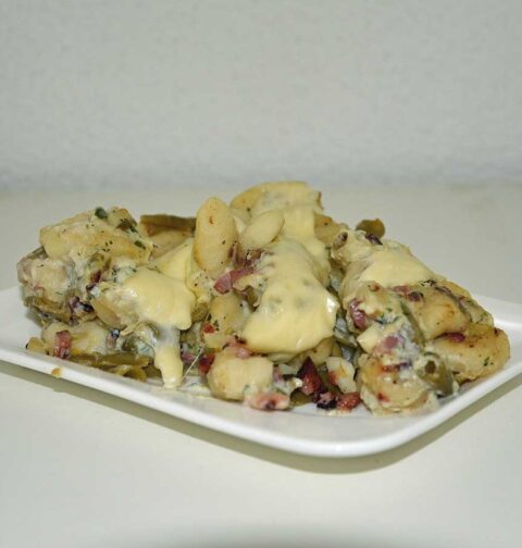 Gnocchi carbonara met bonen op een rechthoekig wit bordje.