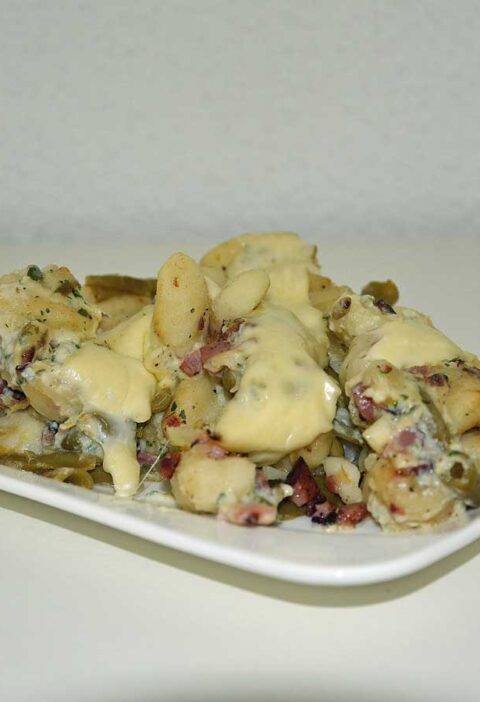 Gnocchi carbonara met bonen op een rechthoekig wit bordje.