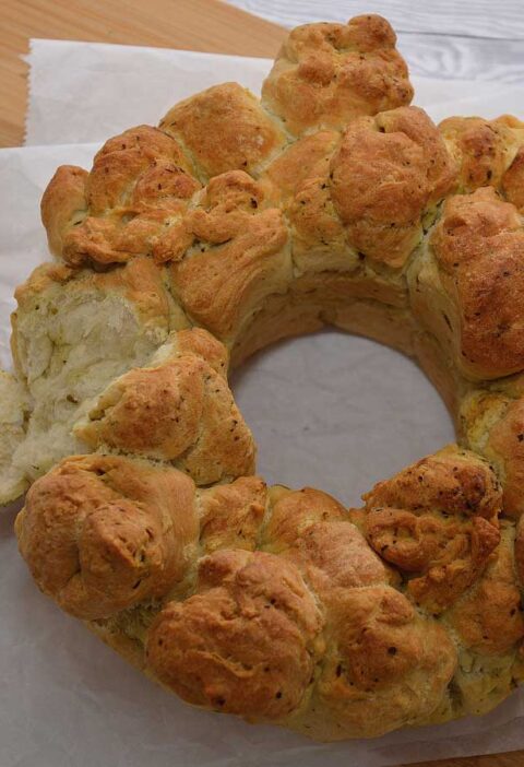 Een heerlijk zelf gebakken plukbrood met pesto, met een stuk eraf geplukt.