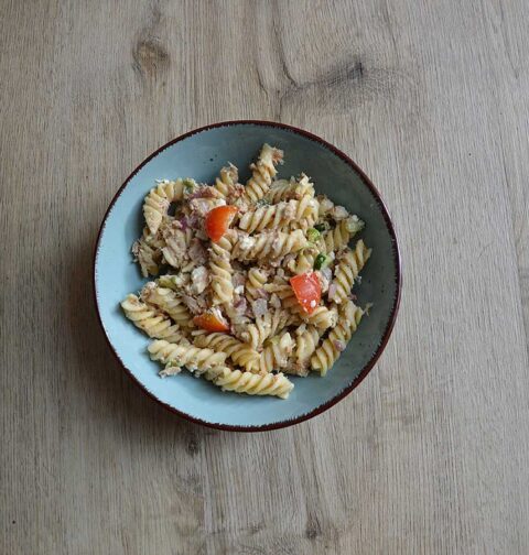 Koudepastasalade met tonijn in een lichtblauw schaaltje.
