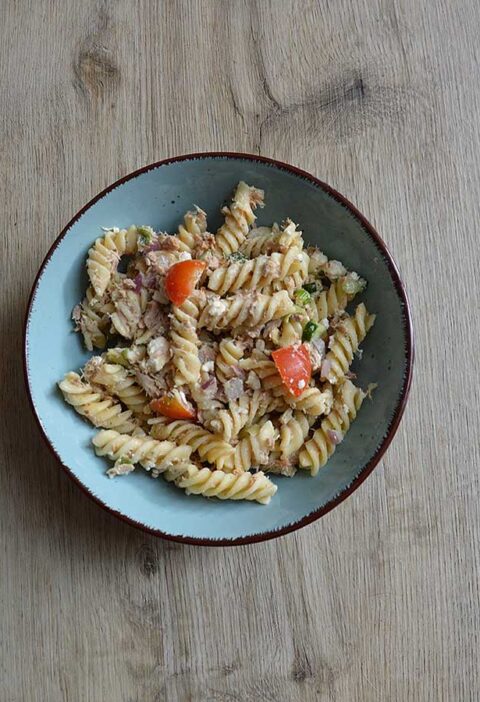 Koudepastasalade met tonijn in een lichtblauw schaaltje.