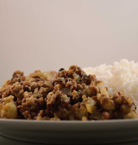 Linzen Bloemkool Curry met rijst, op een wit bord.