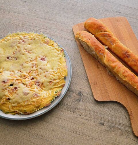 Omelet met worst en kaas op een bruine ondergrond.