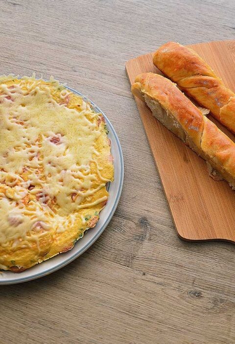 Omelet met worst en kaas op een bruine ondergrond.