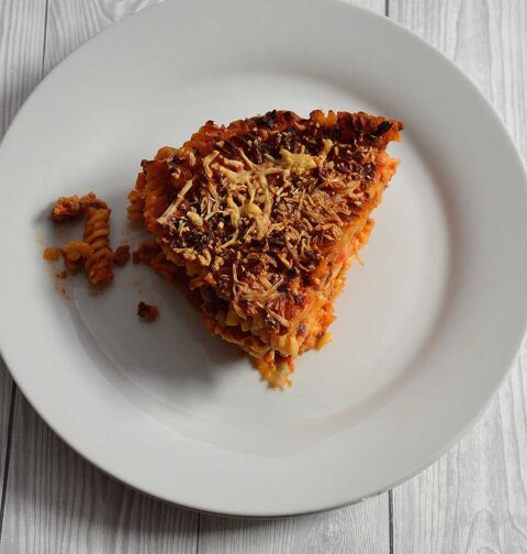 Een stuk pastataart Bolognese op een wit bord.