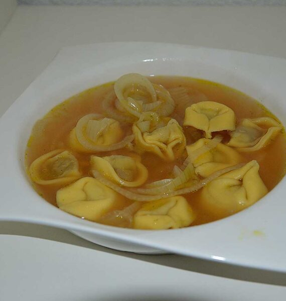 Een soepbord met uiensoep met tortellini.