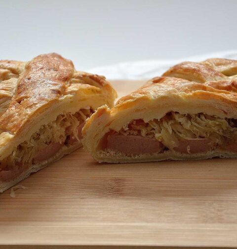Zuurkoolstrudel met rookworst. doormidden gesneden zodat je de zuurkool en stukken rookworst kunt zien.