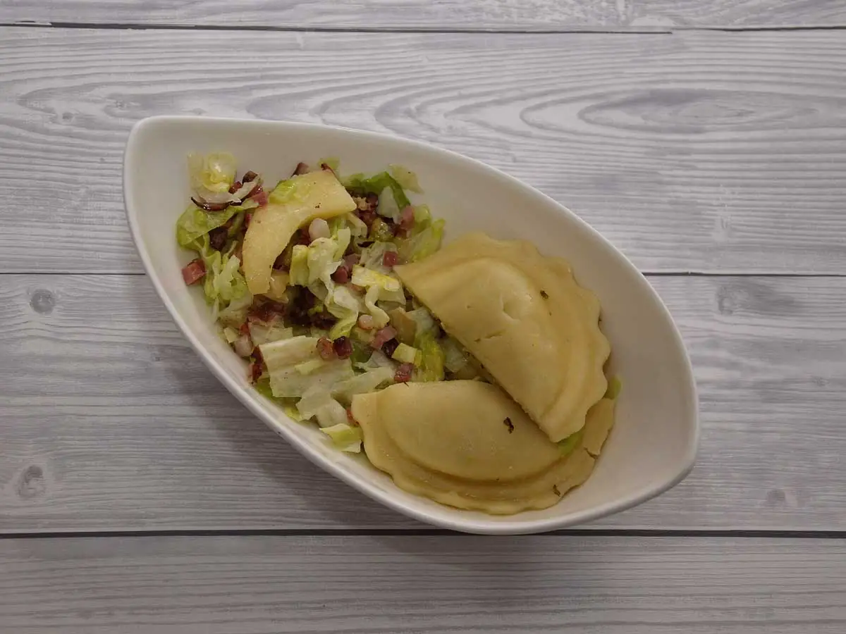 Appel spek salade met ravioli in een wit schaaltje.