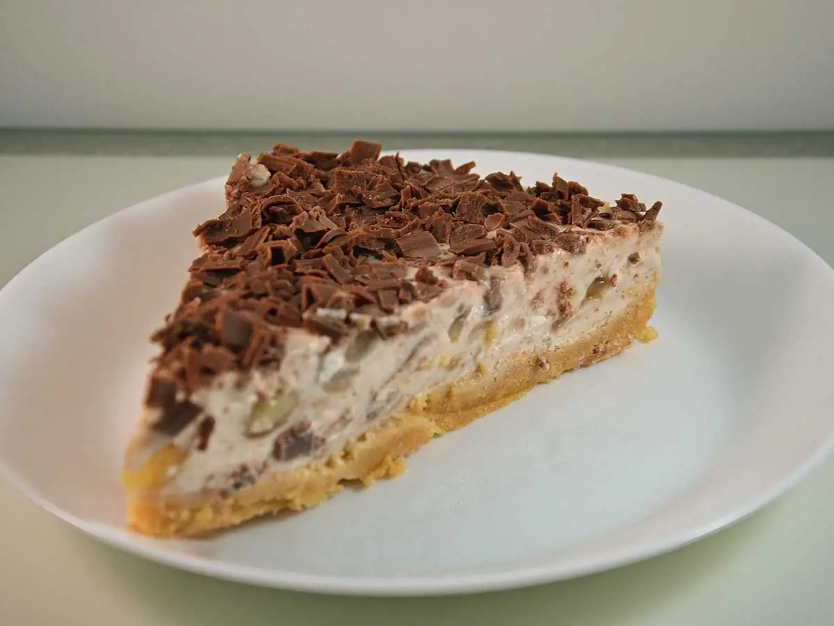 Een stuk banaan kwarktaart met chocolade op een wit bord.