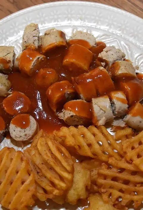 Een bord met zelfgemaakte Duitse curryworst en wafelpatat uit de aanbieding.