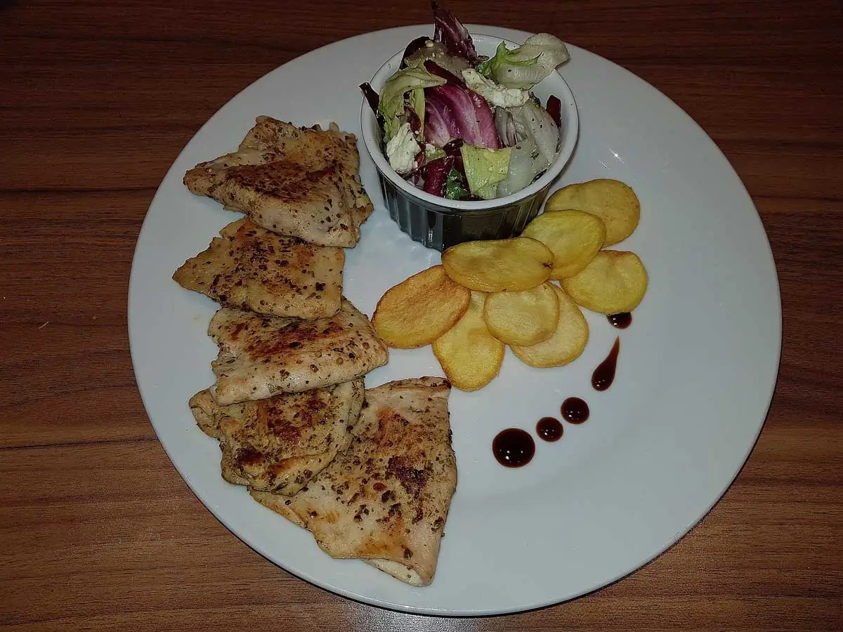 Gevulde kipschnitzel met feta, naast een salade en gefrituurde aardappelschijfjes.