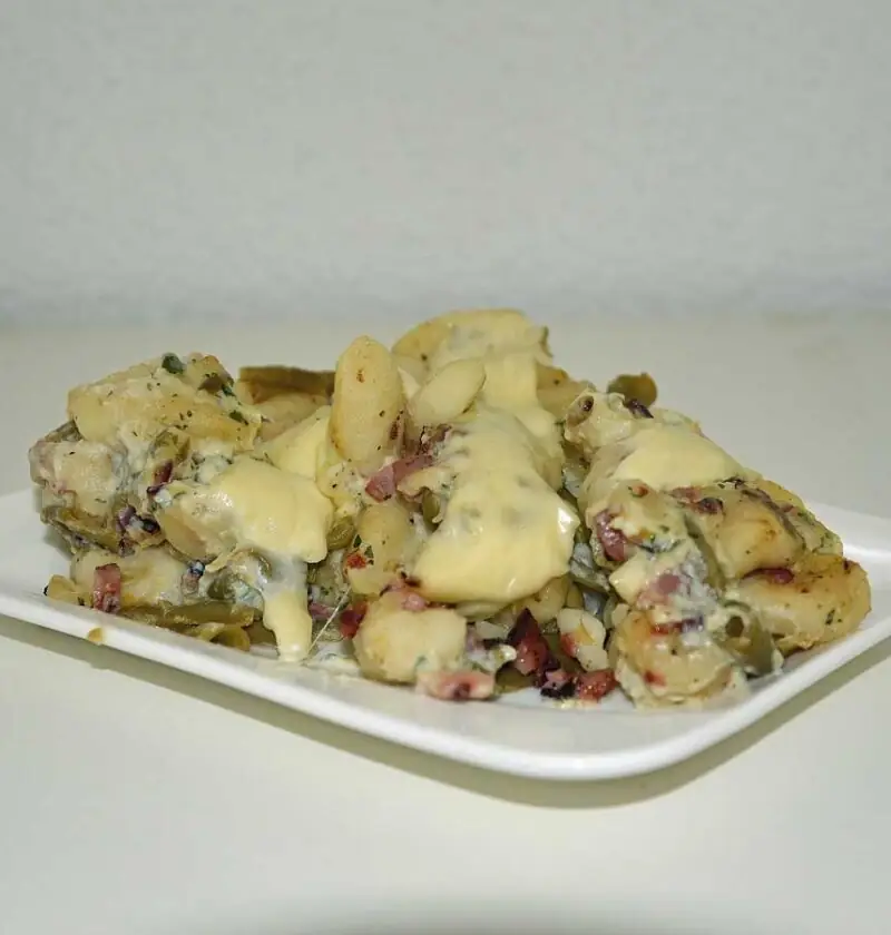 Gnocchi carbonara met bonen op een rechthoekig wit bordje.