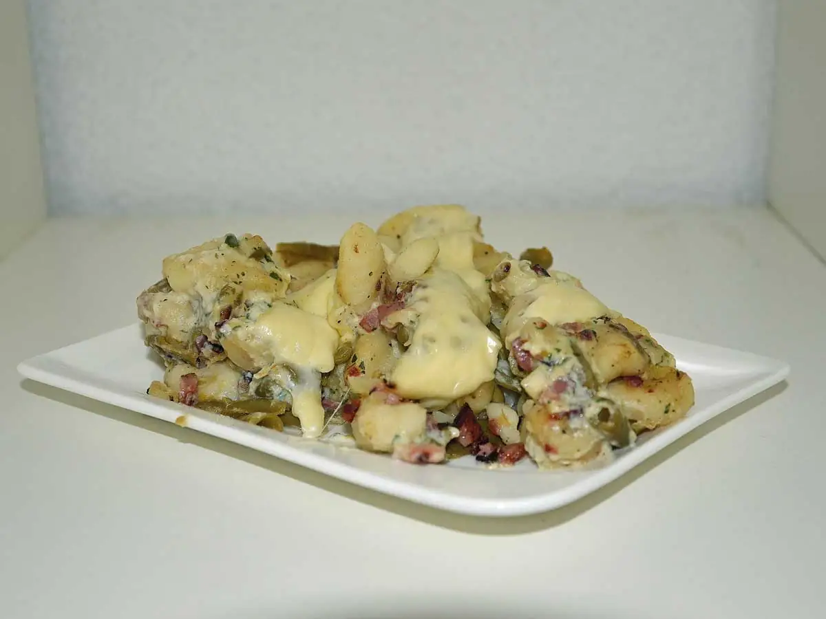 Gnocchi carbonara met bonen op een rechthoekig wit bordje.