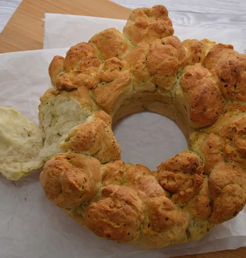 Een heerlijk zelf gebakken plukbrood met pesto, met een stuk eraf geplukt.