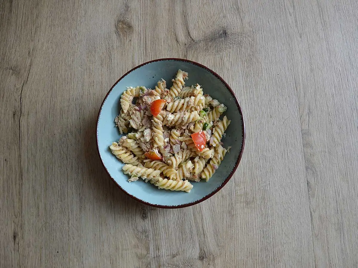 Koudepastasalade met tonijn in een lichtblauw schaaltje.