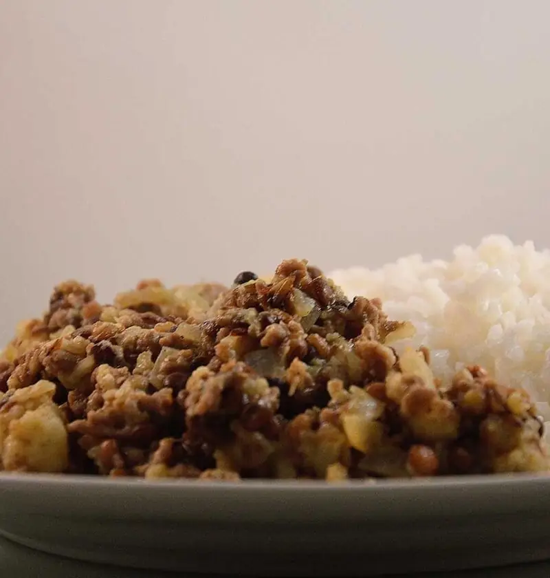 Linzen Bloemkool Curry met rijst, op een wit bord.