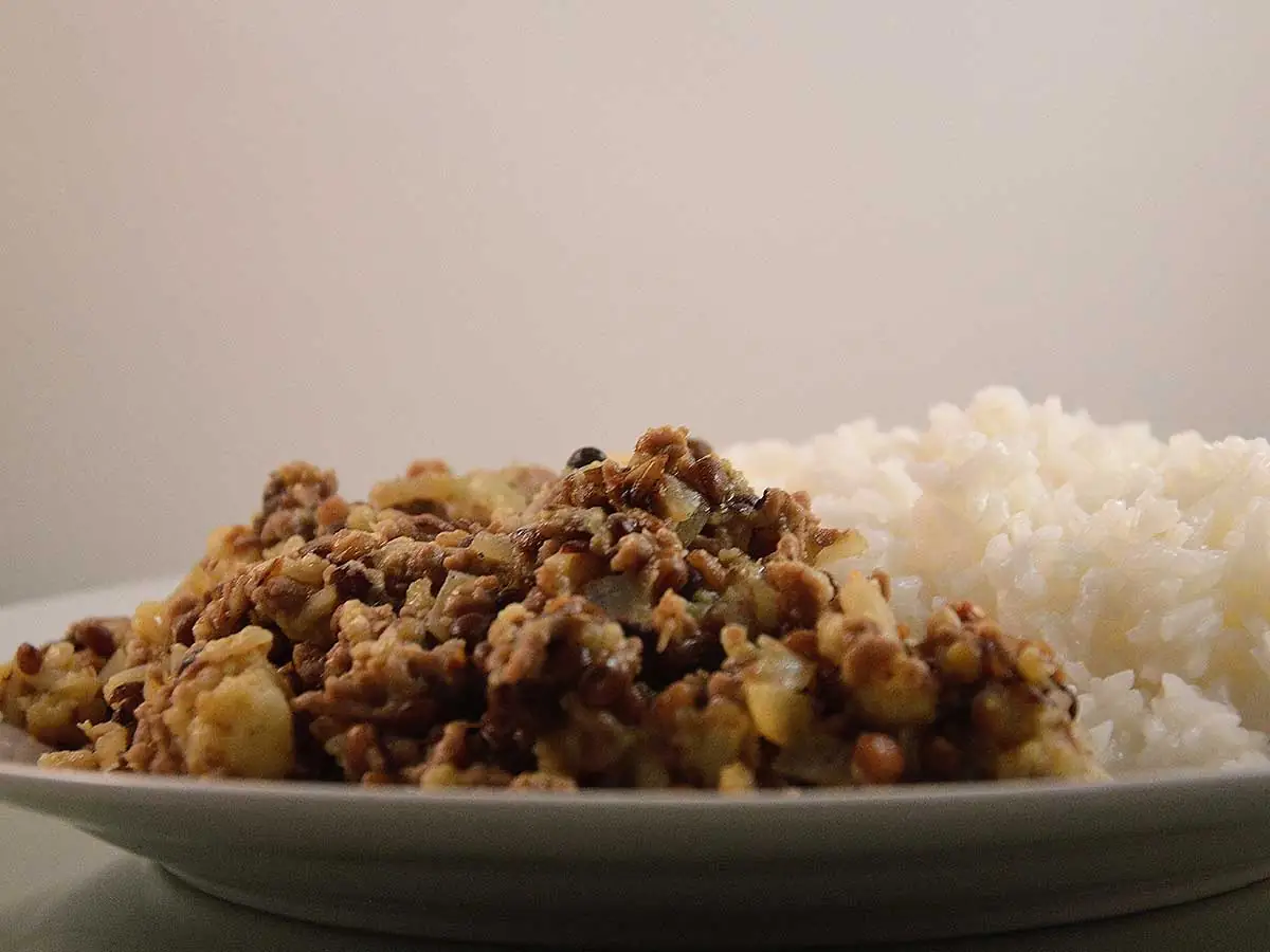 Linzen Bloemkool Curry met rijst, op een wit bord.
