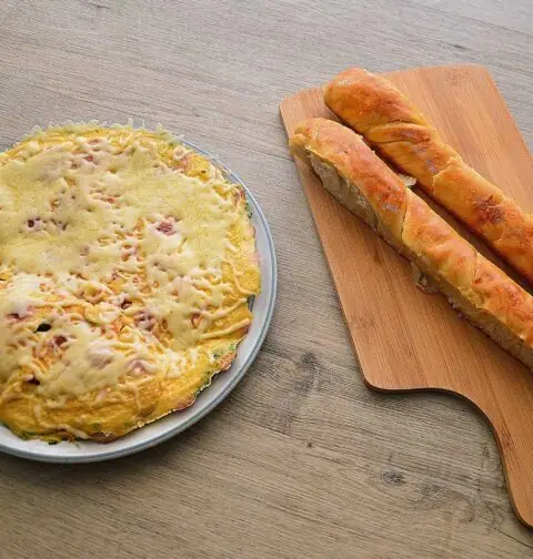 Omelet met worst en kaas op een bruine ondergrond.