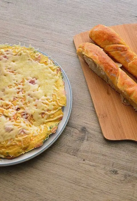 Omelet met worst en kaas op een bruine ondergrond.