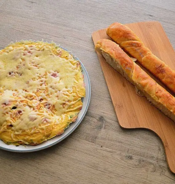 Omelet met worst en kaas op een bruine ondergrond.