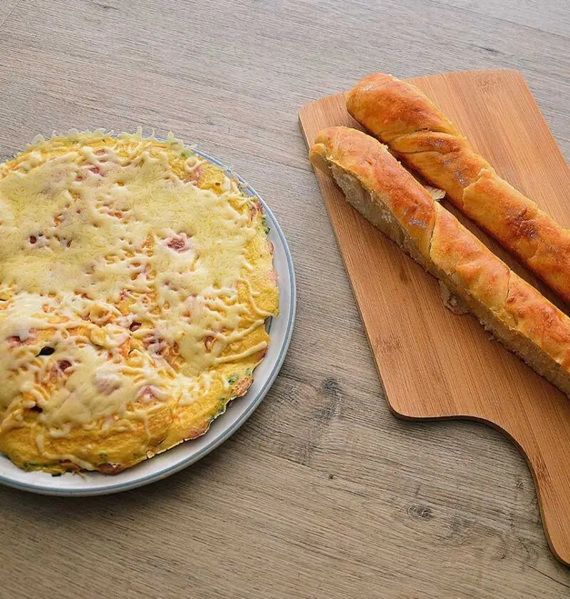 Omelet met worst en kaas op een bruine ondergrond.