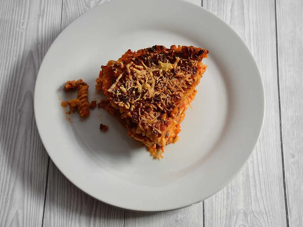 Een stuk pastataart Bolognese op een wit bord.