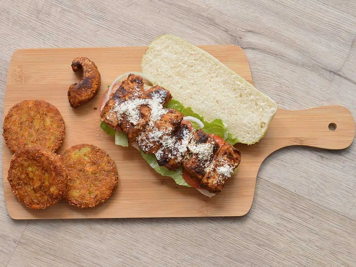 Een pesto broodje met gekruidekip op een snijplank.